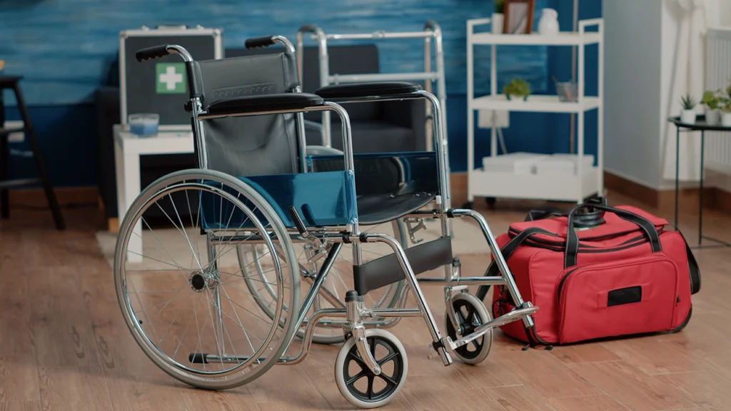 empty wheelchair in a nursing home with a red bag sitting on the floor next to it