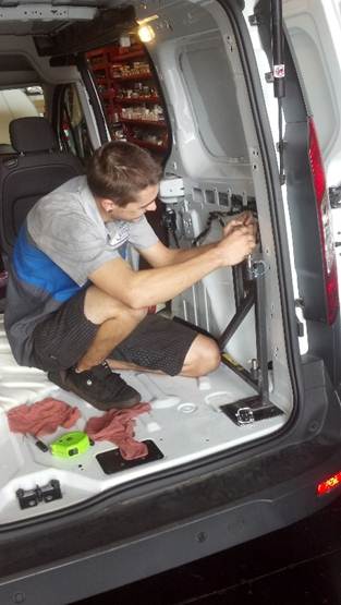 Man installing mobility upgrades to back of van